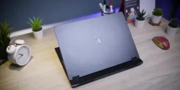 Review Acer Nitro 16S AI menampilkan desain cover sasis belakang yang minimalis dan elegan di atas meja kerja dengan setup modern.