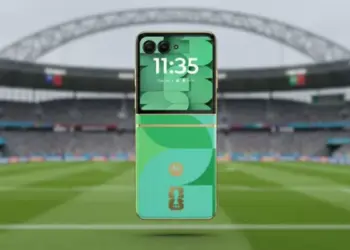 Smartphone lipat Motorola Razr 50 Edisi Khusus Piala Dunia 2026 berwarna hijau dengan latar belakang stadion sepak bola.