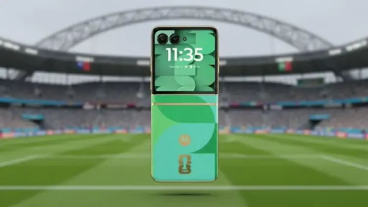 Smartphone lipat Motorola Razr 50 Edisi Khusus Piala Dunia 2026 berwarna hijau dengan latar belakang stadion sepak bola.
