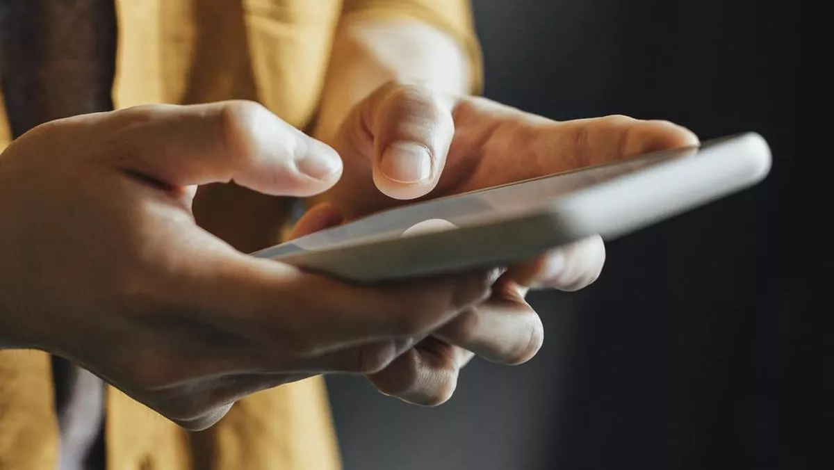 Tangan pengguna yang sedang menavigasi layar smartphone untuk cek tipe HP melalui menu pengaturan sistem.