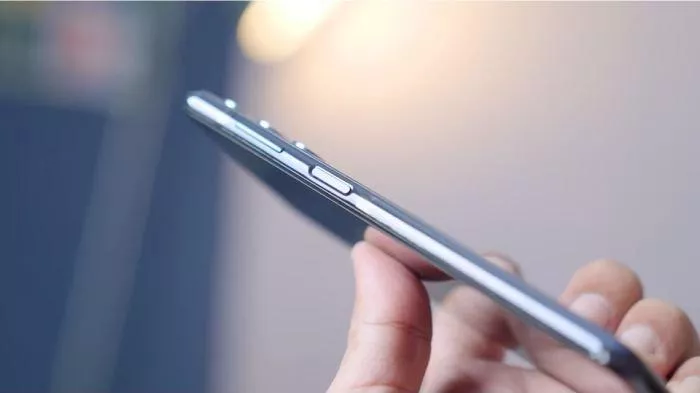 Foto close-up sisi samping smartphone yang menunjukkan tombol power yang sudah aus atau rusak, memerlukan cara menghidupkan HP tanpa tombol.