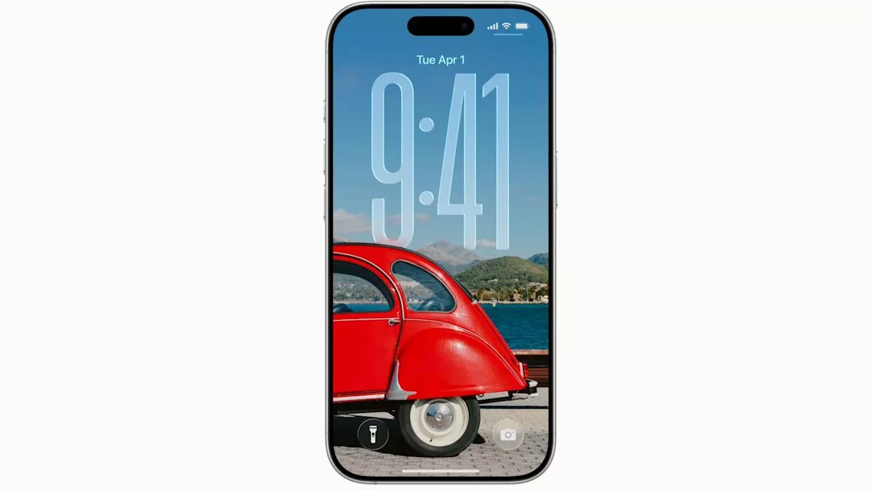 Tampilan Layar Kunci iPhone dengan jam digital besar dan wallpaper mobil merah, menampilkan antarmuka utama iOS 26.2.