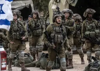 Sekelompok tentara Militer Israel berhelm dan seragam tempur berdiri berkelompok dengan bendera Israel, menunjukkan pasukan bersenjata.