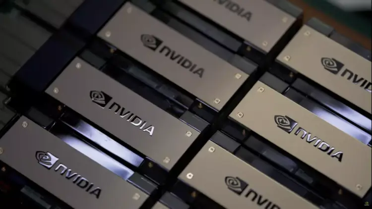 Tumpukan chip atau kartu grafis dengan logo NVIDIA berwarna emas di gudang pabrik, mengindikasikan peningkatan produksi Chip H200.