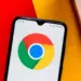 Smartphone dengan latar belakang teknologi, menyimbolkan masalah keamanan data atau konflik software antara Apple dan Google Chrome.