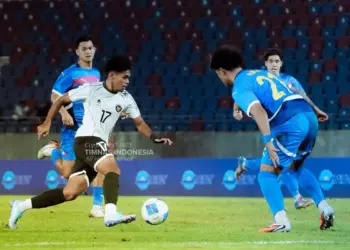 Pemain Timnas U23 Indonesia (kaos putih no. 17) mendribel bola melewati hadangan dua pemain lawan di stadion yang terisi sebagian.