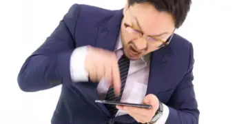 Seorang pria sedang fokus menatap layar smartphone saat bermain game dalam posisi lanskap.