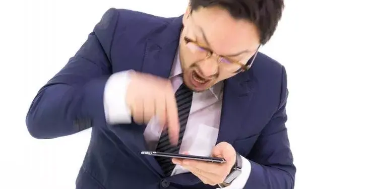 Seorang pria sedang fokus menatap layar smartphone saat bermain game dalam posisi lanskap.