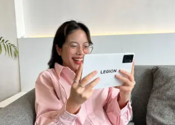 Seorang gamer tersenyum gembira saat menggunakan tablet Lenovo Legion Tab Gen 3 berwarna putih, ditenagai Snapdragon 8 Gen 3 untuk pengalaman bermain game yang lancar.