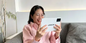 Seorang gamer tersenyum gembira saat menggunakan tablet Lenovo Legion Tab Gen 3 berwarna putih, ditenagai Snapdragon 8 Gen 3 untuk pengalaman bermain game yang lancar.