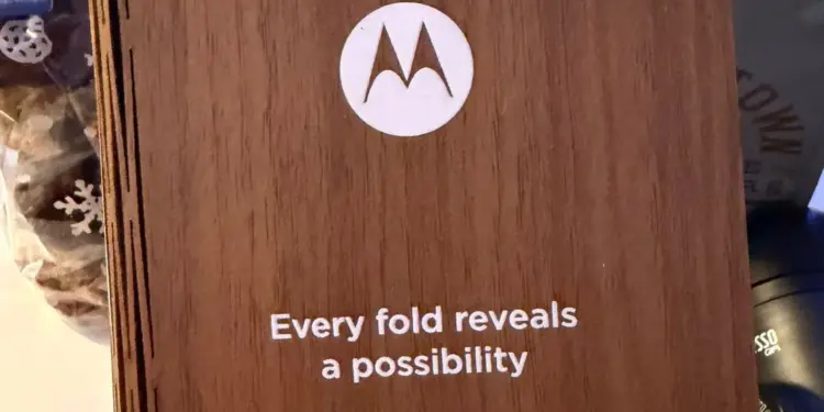 Teaser resmi HP lipat buku Motorola terbaru berupa undangan kayu dengan tulisan Every fold reveals a possibility untuk peluncuran Januari 2026