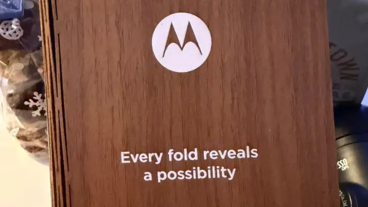 Teaser resmi HP lipat buku Motorola terbaru berupa undangan kayu dengan tulisan Every fold reveals a possibility untuk peluncuran Januari 2026
