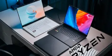 Setup studio menampilkan rekomendasi laptop AMD Ryzen terbaik 2025, termasuk Asus Zenbook putih dan Razer Blade hitam dengan logo AMD Ryzen.