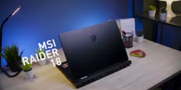 Review MSI Raider 18 HX AI tampak belakang di atas meja kerja, menampilkan desain premium laptop gaming flagship dengan logo naga MSI.
