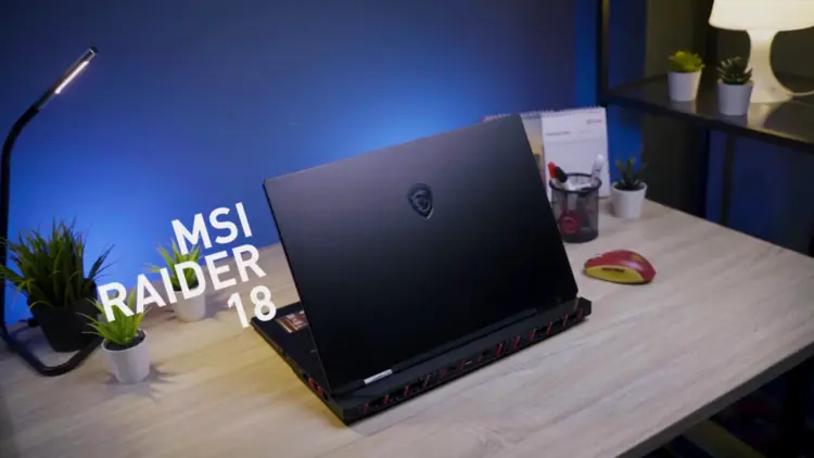 Review MSI Raider 18 HX AI tampak belakang di atas meja kerja, menampilkan desain premium laptop gaming flagship dengan logo naga MSI.