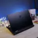 Review MSI Raider 18 HX AI tampak belakang di atas meja kerja, menampilkan desain premium laptop gaming flagship dengan logo naga MSI.