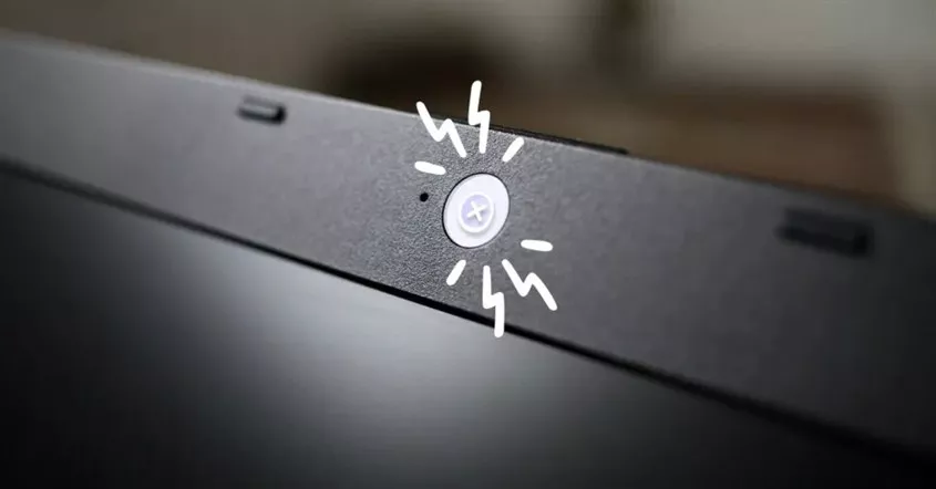 Detail lensa webcam pada bezel laptop hitam dengan ilustrasi cahaya putih sebagai indikator aktif saat Tes Kamera di Windows 11.