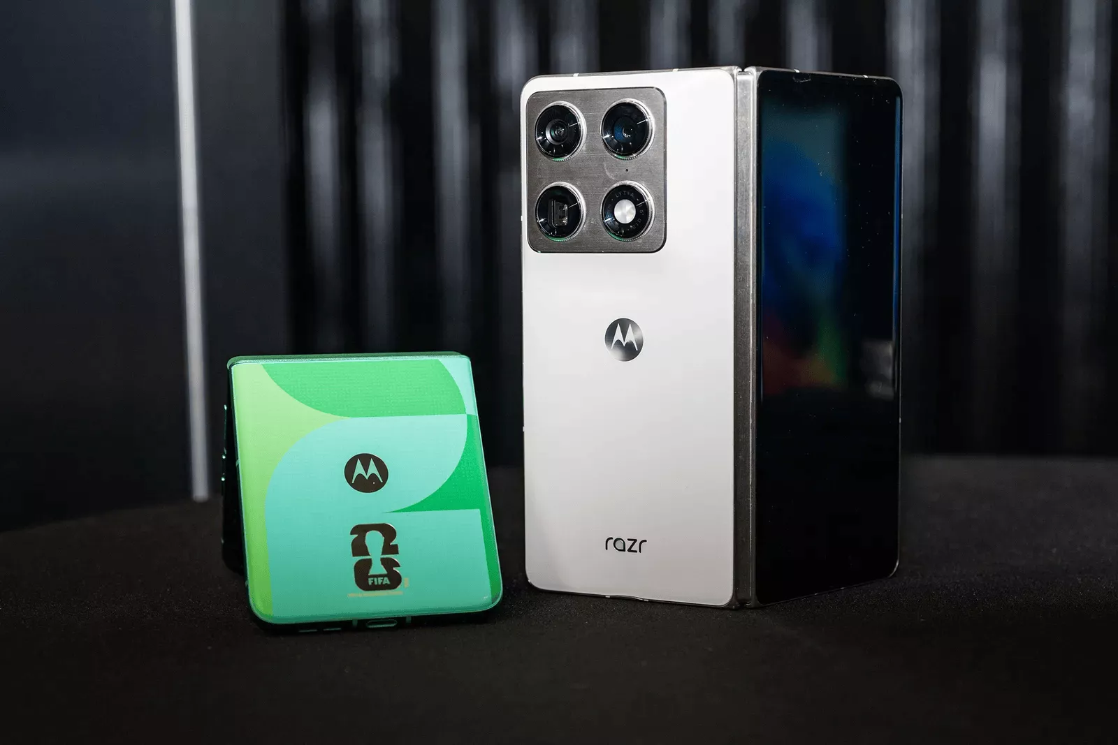 Tampilan panel belakang Motorola Razr Fold berwarna putih dengan modul empat kamera besar di samping unit Razr flip edisi khusus FIFA.