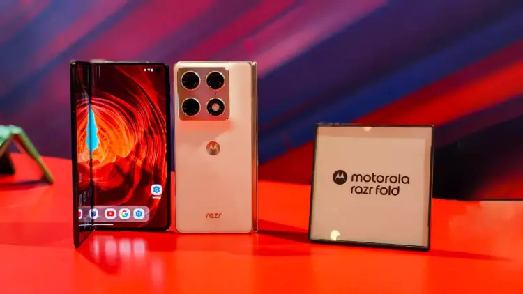 Ponsel Motorola Razr Fold dalam kondisi setengah terlipat di samping papan nama resmi "motorola razr fold" di pameran CES 2026.