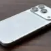 Detail bodi belakang iPhone 18 Pro Max warna putih perak di atas permukaan kayu, menonjolkan logo Apple dan lensa kamera.