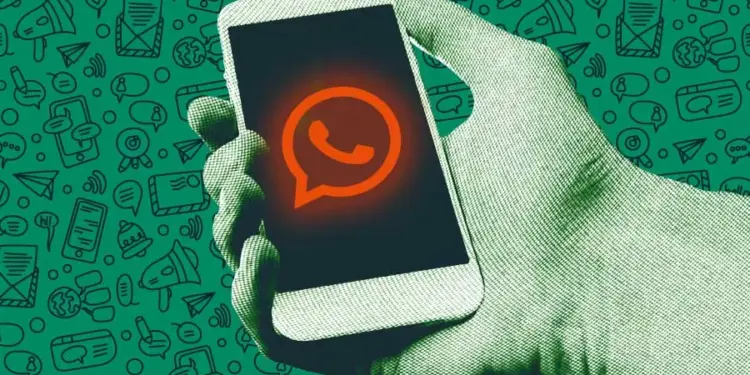 Ilustrasi tangan memegang smartphone dengan logo WhatsApp berwarna oranye kemerahan sebagai simbol bahaya penyadapan dari Aplikasi pihak ketiga.