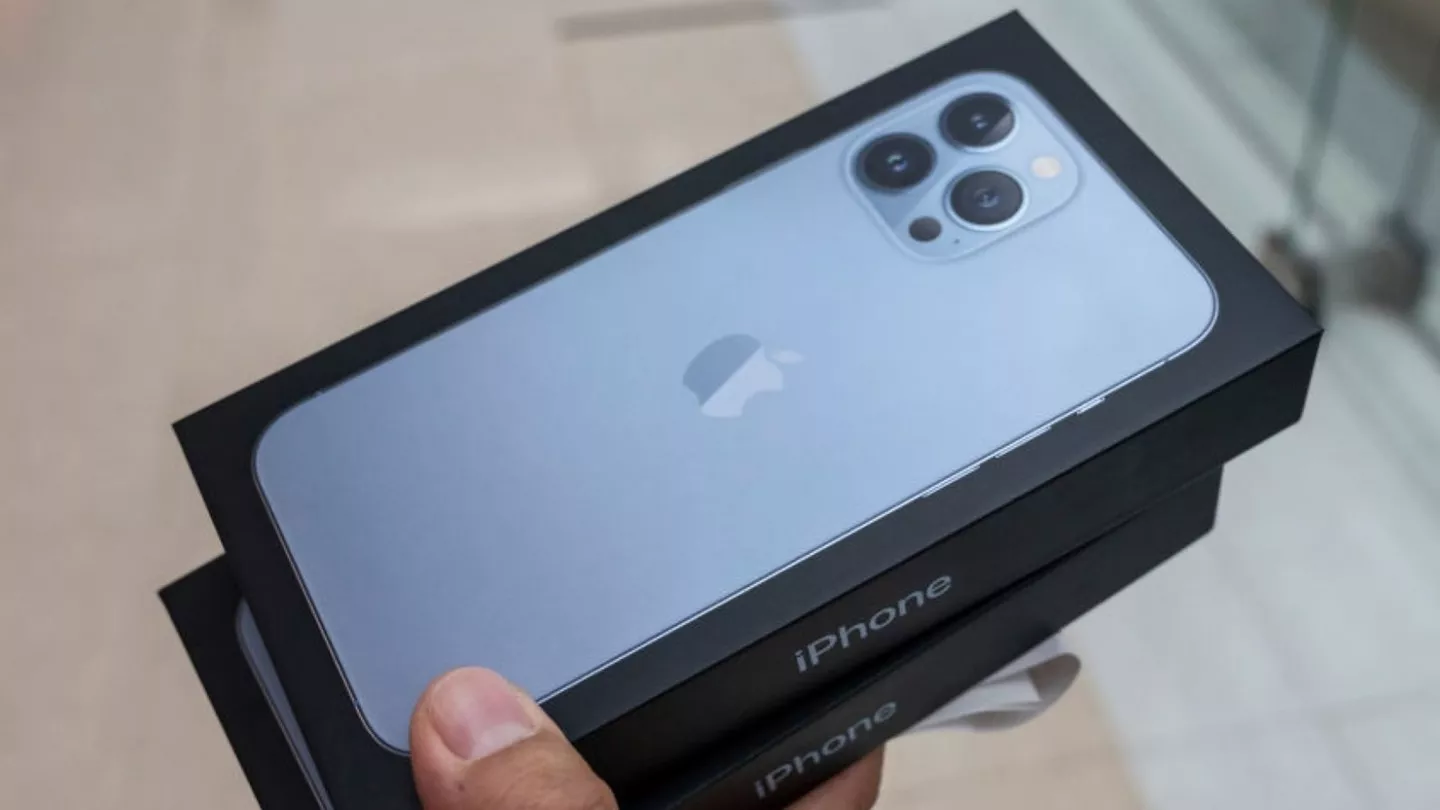 Seseorang memegang kotak kemasan iPhone Pro series setelah beli iPhone baru