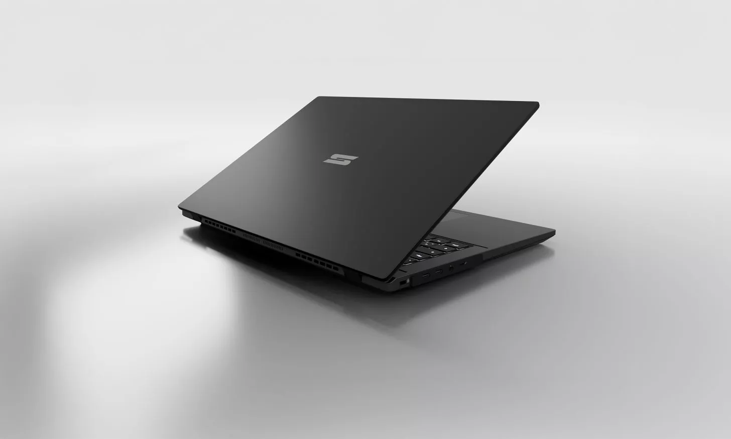Sisi belakang layar laptop Schenker Element 16 warna hitam minimalis dengan logo perak di tengah.
