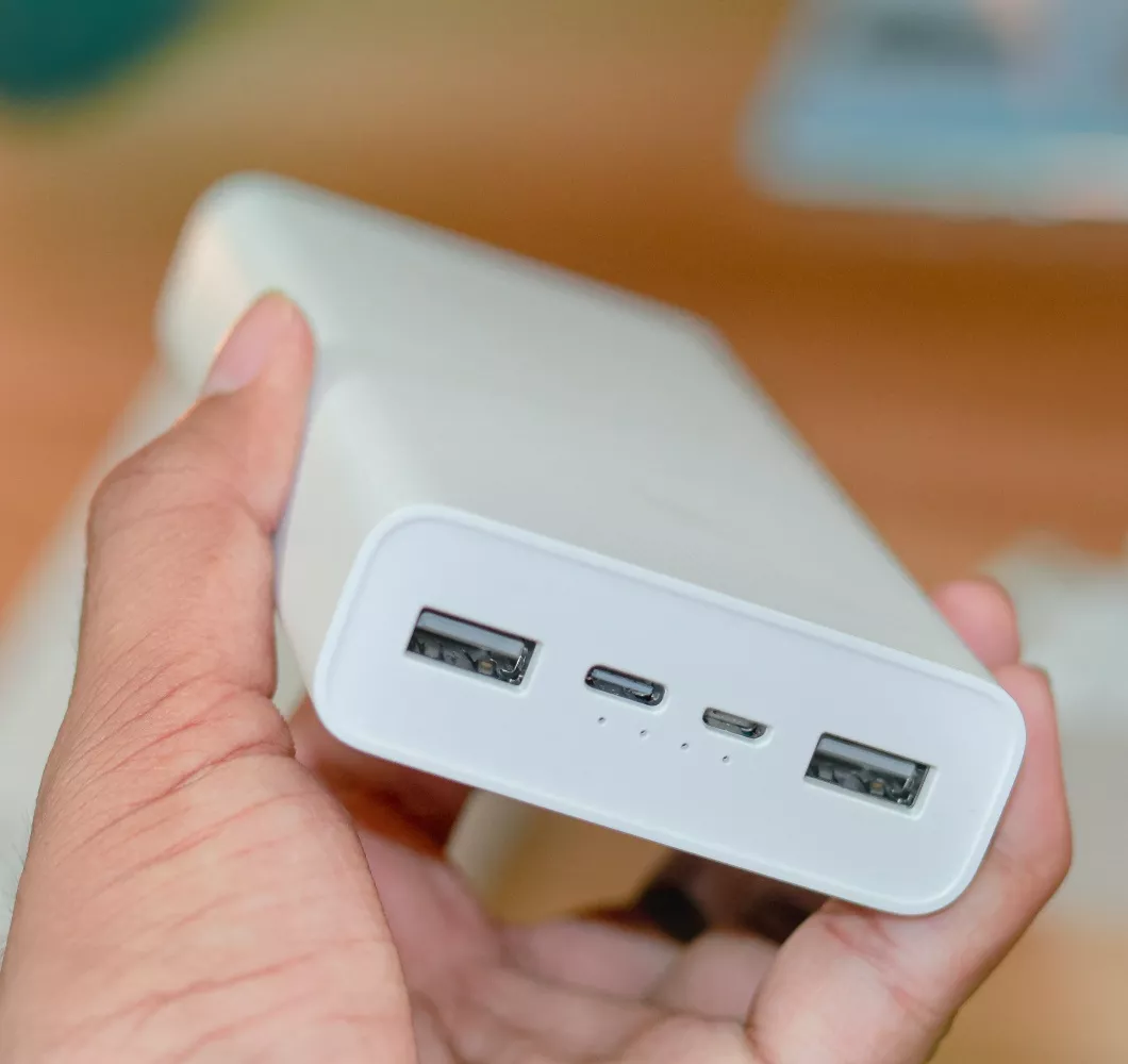 Tampilan dekat (close-up) tangan memegang Powerbank Terbaik 10.000 mAh yang memiliki dua port USB-A, satu port Micro-USB, dan satu port USB-C.
