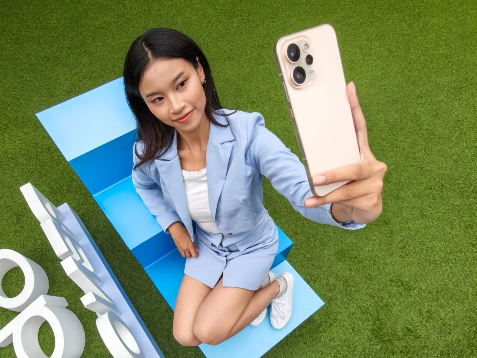 Wanita sedang merekam video atau selfie menggunakan OPPO Reno15 Series varian warna emas.