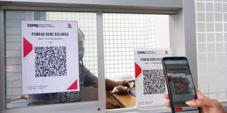 Penggunaan transaksi QRIS untuk pembayaran administrasi di loket pemerintah daerah melalui kaca pembatas.