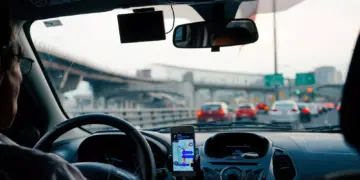 Tampilan dashboard mobil dengan smartphone yang terpasang di holder menampilkan rute navigasi dari aplikasi mudik lebaran.