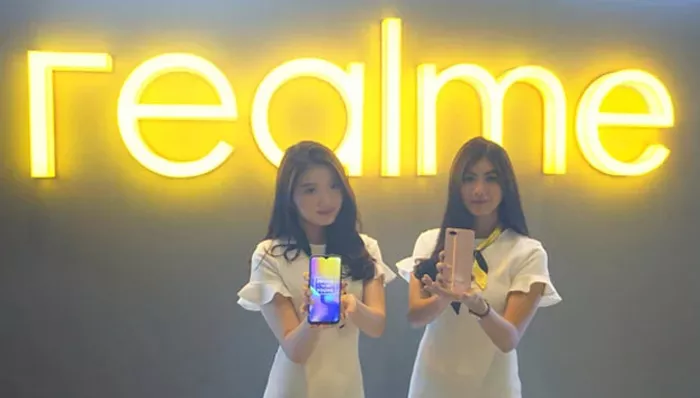 Pelanggan sedang mencoba unit smartphone di Realme Official Store didampingi staf toko.