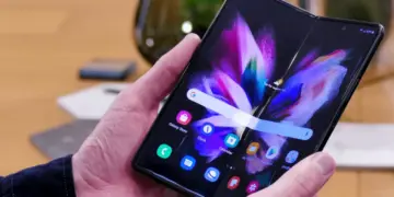 Seorang wanita menggunakan smartphone model terbaru 2026 untuk mengabadikan momen di depan dekorasi lampu.