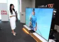 Model sedang memperagakan TV Mini LED 100 Inci LG QNED evo AI terbaru yang memberikan pengalaman bioskop di rumah.