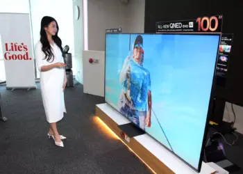 Model sedang memperagakan TV Mini LED 100 Inci LG QNED evo AI terbaru yang memberikan pengalaman bioskop di rumah.