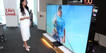 Model sedang memperagakan TV Mini LED 100 Inci LG QNED evo AI terbaru yang memberikan pengalaman bioskop di rumah.