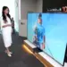 Model sedang memperagakan TV Mini LED 100 Inci LG QNED evo AI terbaru yang memberikan pengalaman bioskop di rumah.