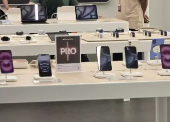 Alt Text (Teks Alternatif): Deretan iPhone 15 dan iPhone 16 dipajang di atas meja display putih di dalam toko iBox Indonesia dengan tanda promosi iPhone 16 Pro.