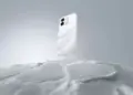 Desain bodi belakang OPPO A6s berwarna putih dengan tekstur gelombang halus menyerupai kerang mutiara yang melayang di atas permukaan salju.
