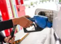 Petugas SPBU memasukkan nozzle pengisian BBM ke tangki mobil, ilustrasi kenaikan harga Pertamax dan jenis BBM lainnya.