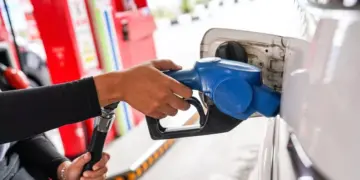 Petugas SPBU memasukkan nozzle pengisian BBM ke tangki mobil, ilustrasi kenaikan harga Pertamax dan jenis BBM lainnya.