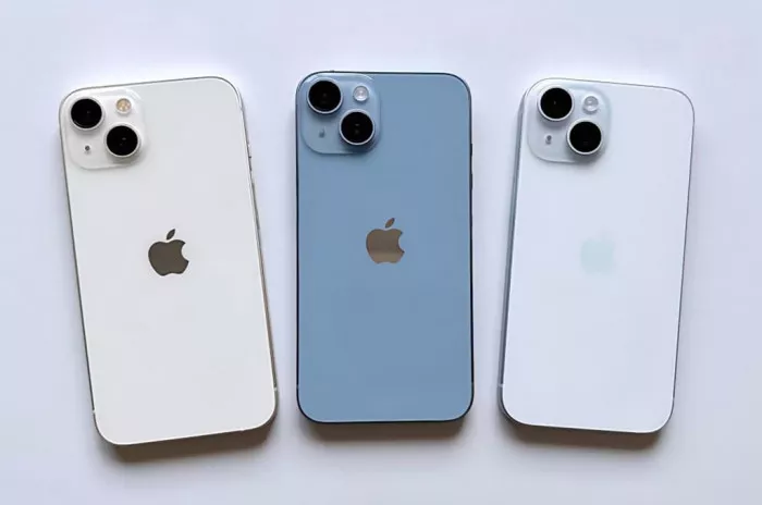 Tiga unit iPhone 15 standar disejajarkan di atas permukaan putih, menampilkan warna Pink pucat, Biru muda, dan Kuning pucat.