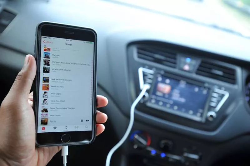 Pengguna memilih daftar putar di aplikasi musik gratis pada smartphone yang terhubung ke head unit mobil melalui kabel USB.