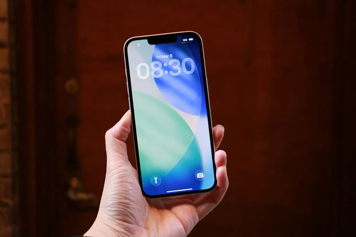 Seseorang memegang iPhone 17e yang menyala, menampilkan antarmuka iOS yang jernih dan bezel tipis.