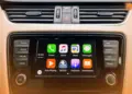 Tampilan antarmuka Apple CarPlay pada layar dashboard mobil yang menunjukkan ikon aplikasi musik gratis dan navigasi.