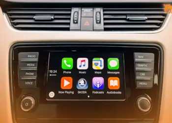 Tampilan antarmuka Apple CarPlay pada layar dashboard mobil yang menunjukkan ikon aplikasi musik gratis dan navigasi.