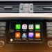 Tampilan antarmuka Apple CarPlay pada layar dashboard mobil yang menunjukkan ikon aplikasi musik gratis dan navigasi.