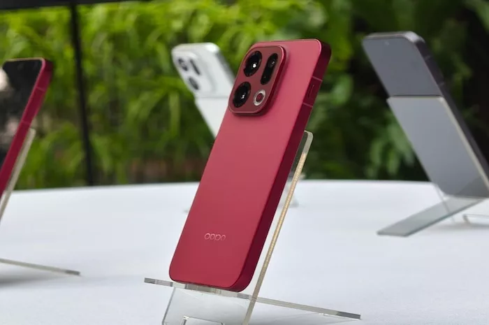 Smartphone Oppo berwarna merah dengan modul kamera unik yang dipajang di atas meja, kemungkinan seri Find X terbaru yang jadwal rilisnya dikabarkan mundur.