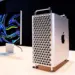 Mac Pro menara diletakkan di atas meja kayu di sebelah Pro Display XDR dengan latar belakang gelap, menunjukkan ekosistem kerja profesional Apple.