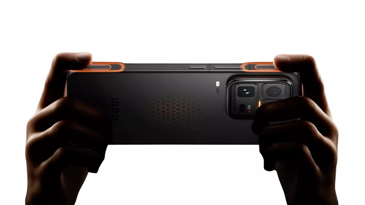 Seseorang memegang iQOO 16 dalam posisi horizontal (landscape) menunjukkan fitur tombol trigger bahu yang menyala oranye untuk pengalaman gaming maksimal.
